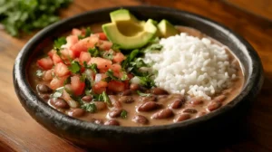 A bowl of cooked habichuelas with rice and fresh vegetables.